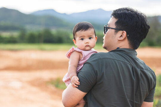 Father holding daughter in arms. Happy asian family child and dad walking outdoor nature. Happy Father's Day