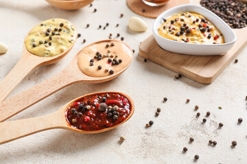 Composition with different sauces and peppercorns on light background