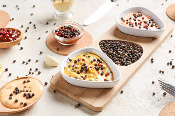 Composition with different sauces and peppercorns on light background