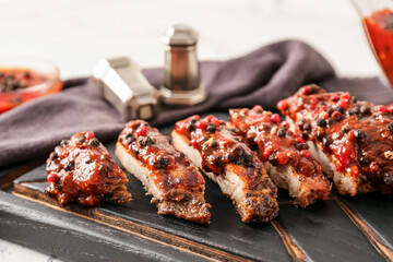 Tasty roasted meat with peppercorn sauce on wooden board, closeup