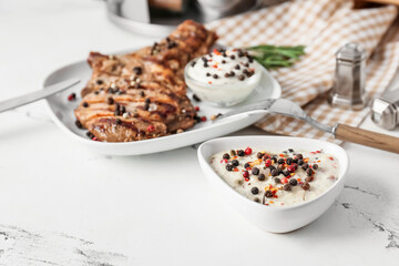 Bowl with peppercorn sauce and roasted meat on light background