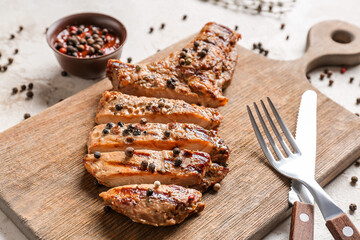 Board with tasty roasted meat and peppercorn sauce on light background, closeup
