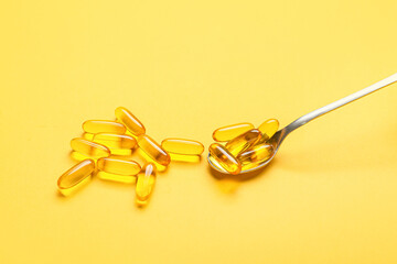 Fototapeta premium Spoon with fish oil capsules on color background