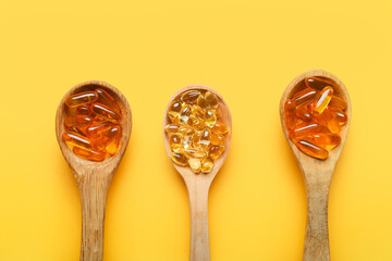 Spoons with fish oil capsules on color background