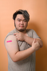 Young man showing vaccinated arm with plaster band. Vaccination and immunization.