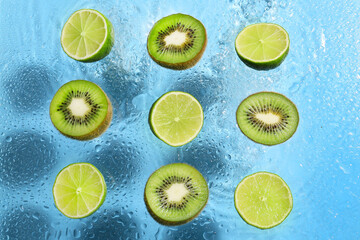Slices of lime and kiwi on color background with water drops