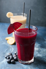 Glasses of healthy smoothie with blueberry, banana and beetroot on color background