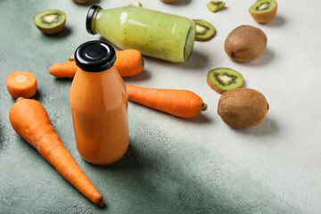 Bottles of healthy smoothie with carrot and kiwi on color background
