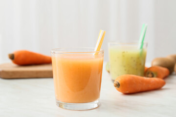 Glasses of healthy smoothie with kiwi and carrot on light background