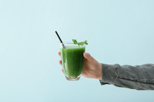 Female hand with glass of healthy green smoothie on color background