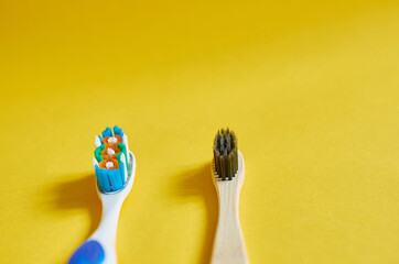 Wooden and plastic toothbrushes on yellow background. Copy space