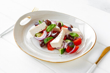 Greek salad in plate on white wooden background