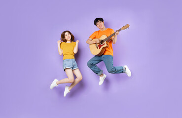 Fototapeta na wymiar Portrait of a couple jumping up, isolated on purple background