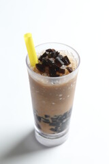 black herbal jelly milk tea / coffee with ice in tall glass drink menu in white background with yellow straw 