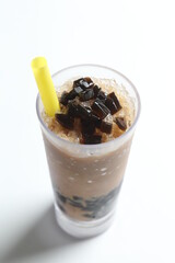 black herbal jelly milk tea / coffee with ice in tall glass drink menu in white background with yellow straw 