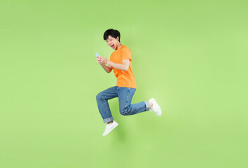 Asian man jumping and holding smartphone , isolated on green