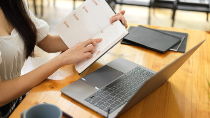 Side view of female office worker checking her schedule while working with laptop