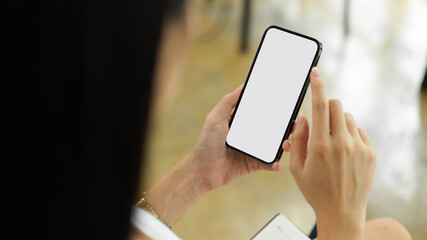 Over shoulder close up view of female using smartphone with mock-up screen