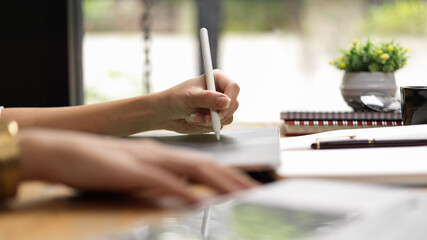 Fototapeta na wymiar Female hand with stylus pen working on digital tablet in office room
