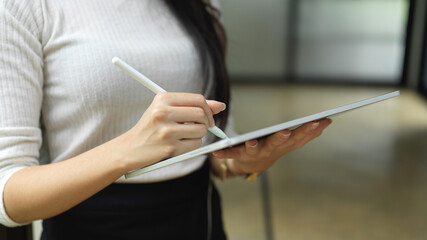 Female hand using digital tablet while standing in office working space