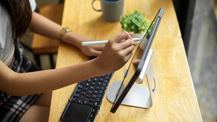 Top view of female hand using digital tablet with stylus pen on the bar in cafe