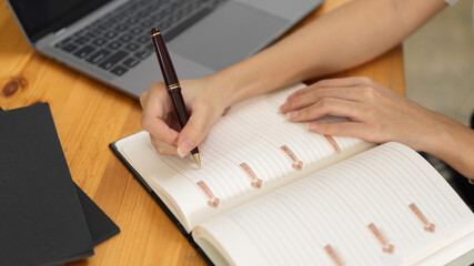 Top view of female handwriting on schedule book while working