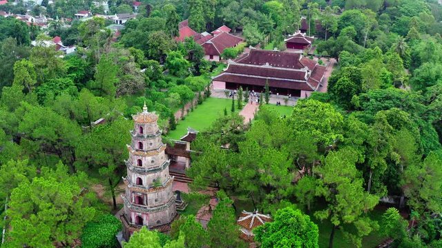 Aerial Shot Of People At Popular Thien Mu Pagoda Amidst Green Trees, Drone Flying Near Famous Buddhist Temple - Hue, Vietnam