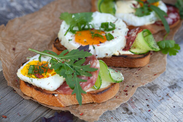 Bruschetta with fried eggs, sausage and herbs.