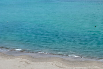 Detail of the turquoise sea with sand on the shore.