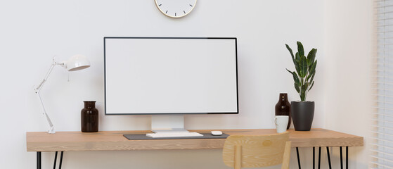 Computer monitor with mock-up screen on wooden table with decorations in minimal room, 3D render