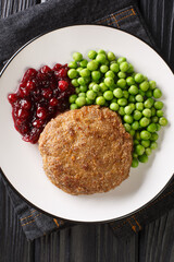 Swedish food Veal burgers Wallenbergare with green peas closeup in the plate on the table. Vertical top view from above