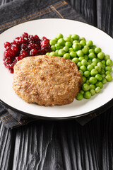 Swedish food Veal burgers Wallenbergare with green peas closeup in the plate on the table. Vertical