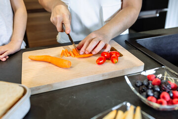 Unrecognizable woman preparing healthy snack with carrot and cherry tomatoes
