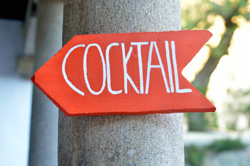 Wooden sign with red arrow indicating cocktail address