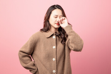 Beautiful oriental woman with uncomfortable nose on pink background