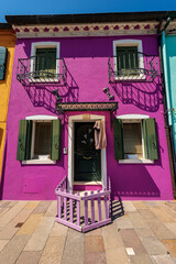 Old small beautiful house with bright colors (magenta and green) in Burano island in a sunny spring day. Venetian lagoon, Venice, UNESCO world heritage site, Veneto, Italy, southern Europe.