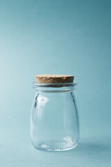 A glass jar with a stopper on a blue background. A jar for cosmetics or water, a place for text.