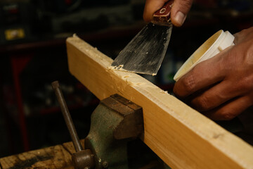 Handyman is smoothing wooden plank with skim coat. Applaying putty on a piece of wood.	
