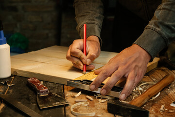 Carpenter measuring and marking wood with speed square measure tool in workshop	