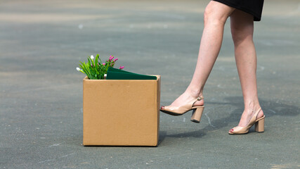 A woman's foot kicks a box personal belongings after being fired close-up.