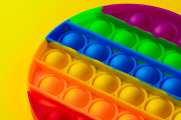 Colorful antistress pop it toy on yellow background