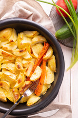 Potatoes and carrots, baked in the oven. Vegetarian dish, close-up.