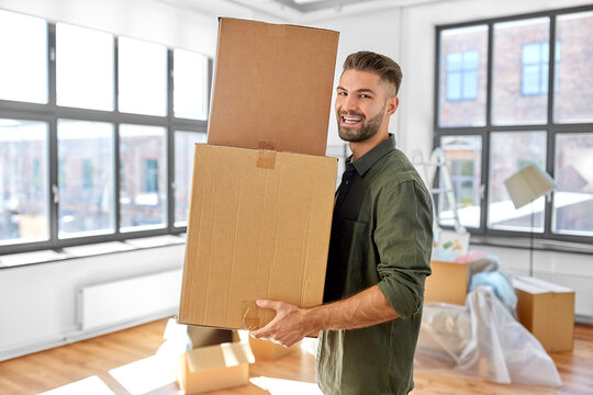 moving, people and real estate concept - happy smiling man holding boxes with stuff at new home
