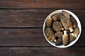 Freshly seasonal morel mushrooms in a white bowl on a old wooden table