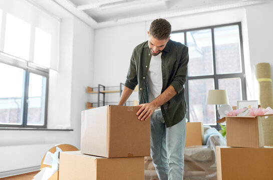 moving, people and real estate concept - happy smiling man with boxes with stuff at new home