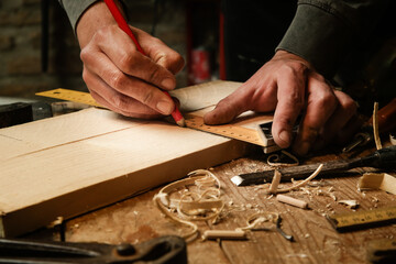 Fototapeta na wymiar Carpenter measuring and marking wood in workshop 