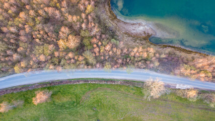 Aerial view of a picturesque place where transparent turquoise water of a forest lake meets a stony shore with trees in spring. captured with a drone. High quality photo