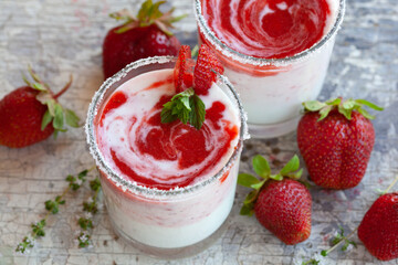 Two glasses of yogurt with strawberries on the table.