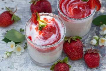 Two glasses of yogurt with strawberries on the table.
