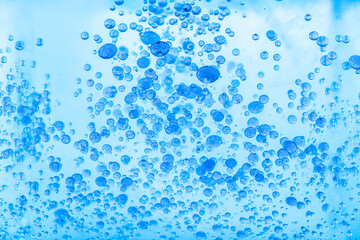 Sky blue paint drops in oil. Macro shot, abstract background with colorful ink and water. Bubbles floating in space and slowly falling. Beautiful acrylic paint. Fluid art, psychedelic wallpaper.
